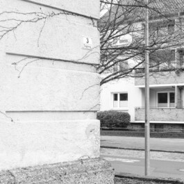 Bunkerwand neben Wohnhäusern mit Hochhaus im Hintergrund 