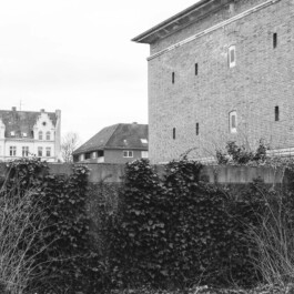 Ziegelbau eines Bunkers hinter bewachsener Mauer in Wohngebiet 